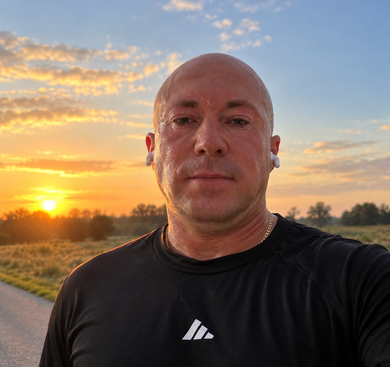 Eugen Pauls im schwarzen Sportshirt mit weißen Kopfhörern vor einem Himmel im goldenen Abendlicht
